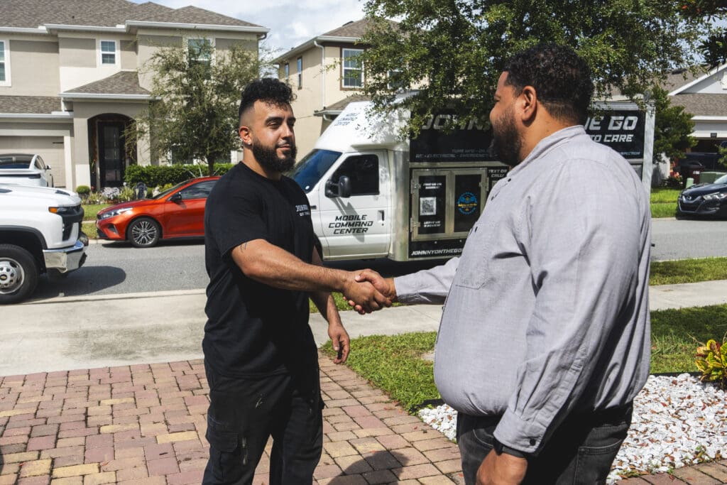 Johnny on the Go technician greeting a customer in his Orlando driveway beside the Mobile Command Center