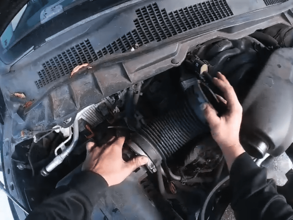 A mechanic's hands work on removing or installing an engine air filter during routine vehicle maintenance.