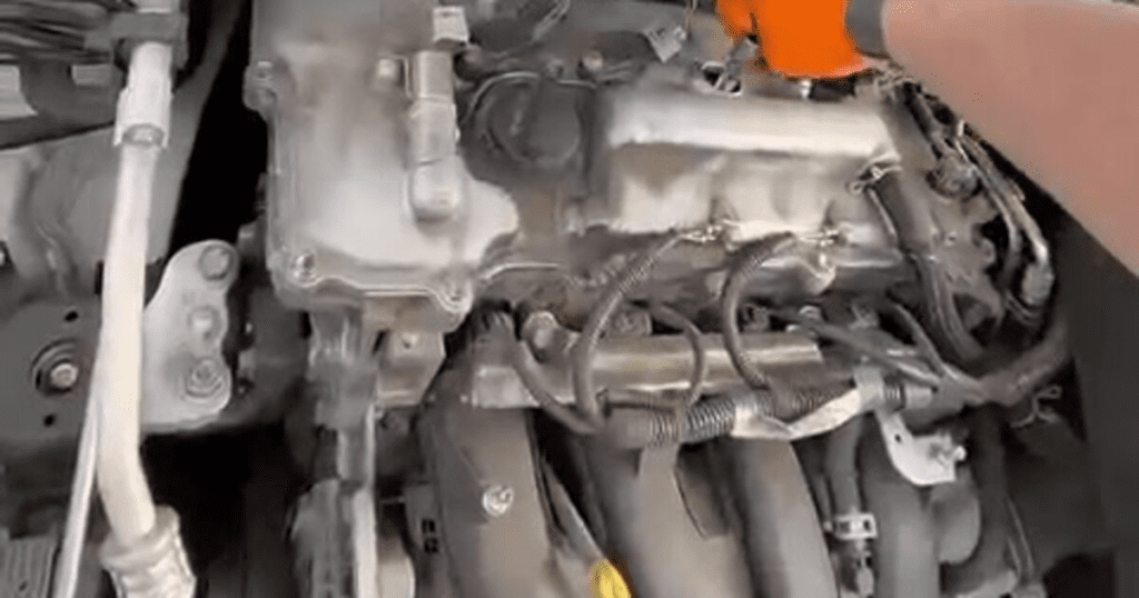 A detailed close-up view of an internal combustion engine showing mechanical components, pistons, and coolant hoses in a workshop or garage setting.