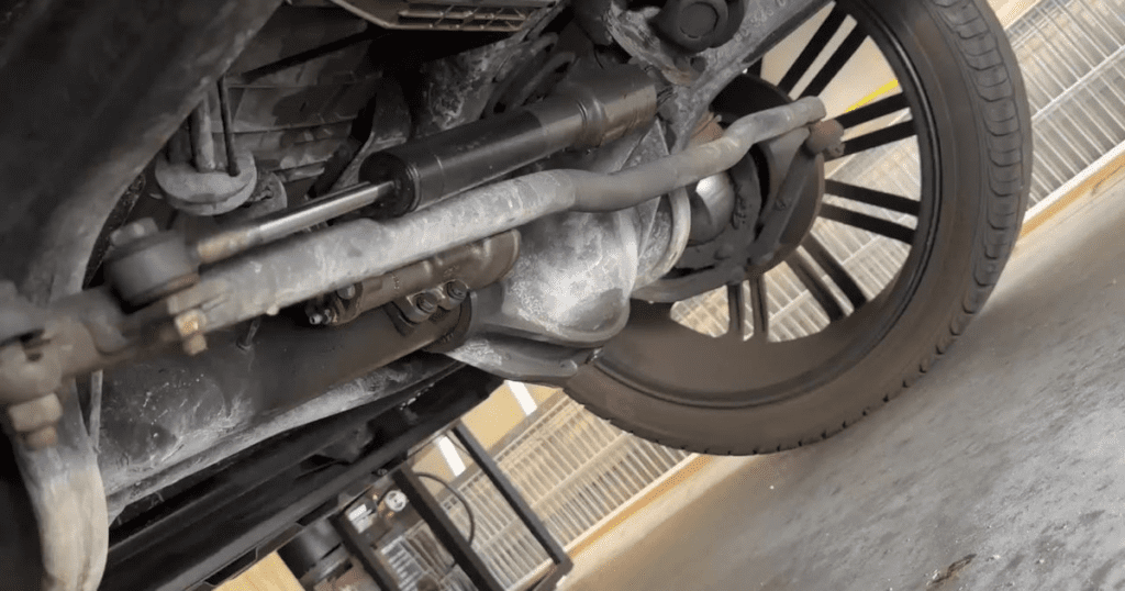 A close-up overhead view of a motorcycle wheel and suspension components on a concrete surface in what appears to be a workshop or repair area.