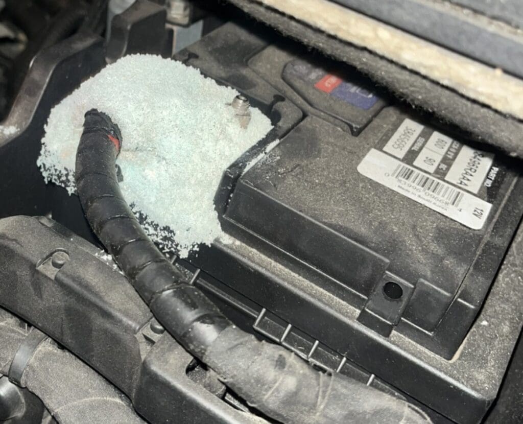 A close-up view of a white engine air filter installed in a vehicle engine bay during maintenance or inspection.
