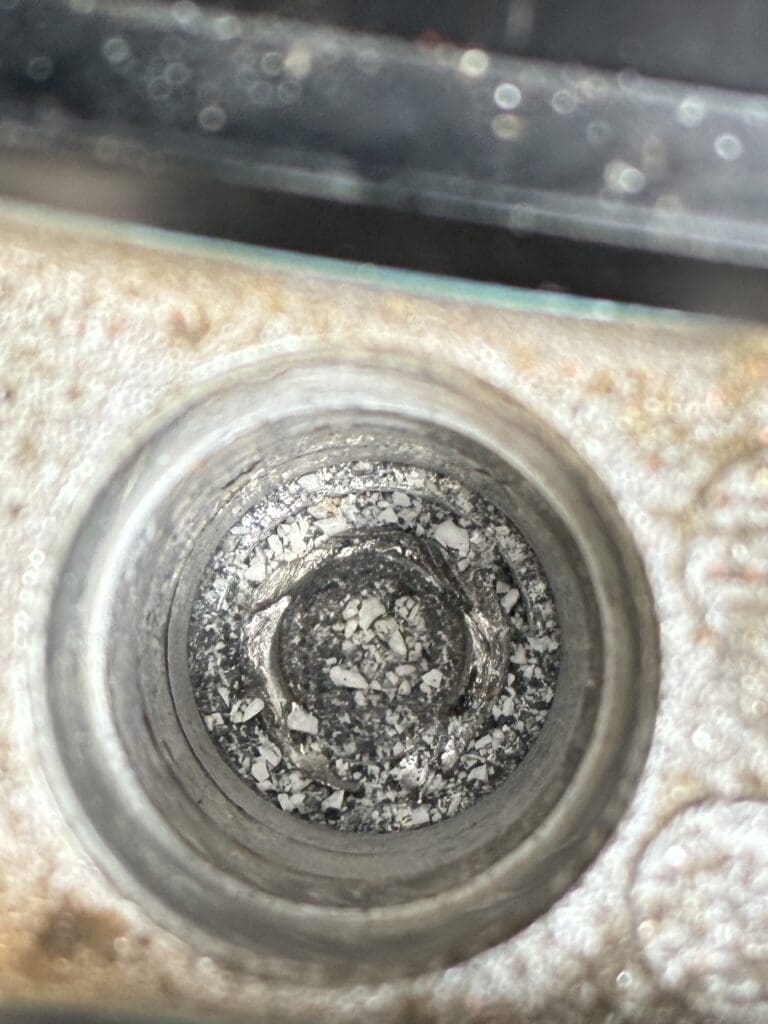 A close-up view of a glass container filled with sparkling glitter or metallic substance on a textured concrete surface.