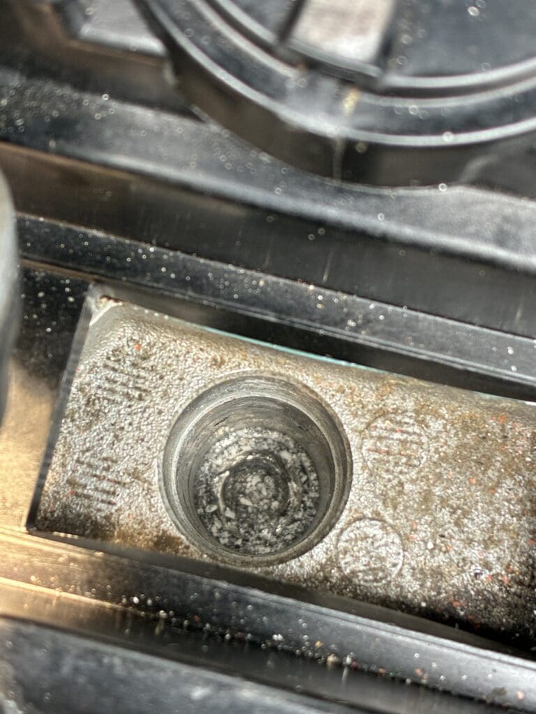 A close-up photograph of a weathered circular gauge or meter mounted on rusty industrial machinery, showing signs of age and oxidation.