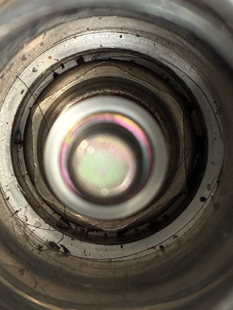 A detailed close-up of a camera lens showing internal optical elements with reflective glass surfaces and metallic aperture rings.
