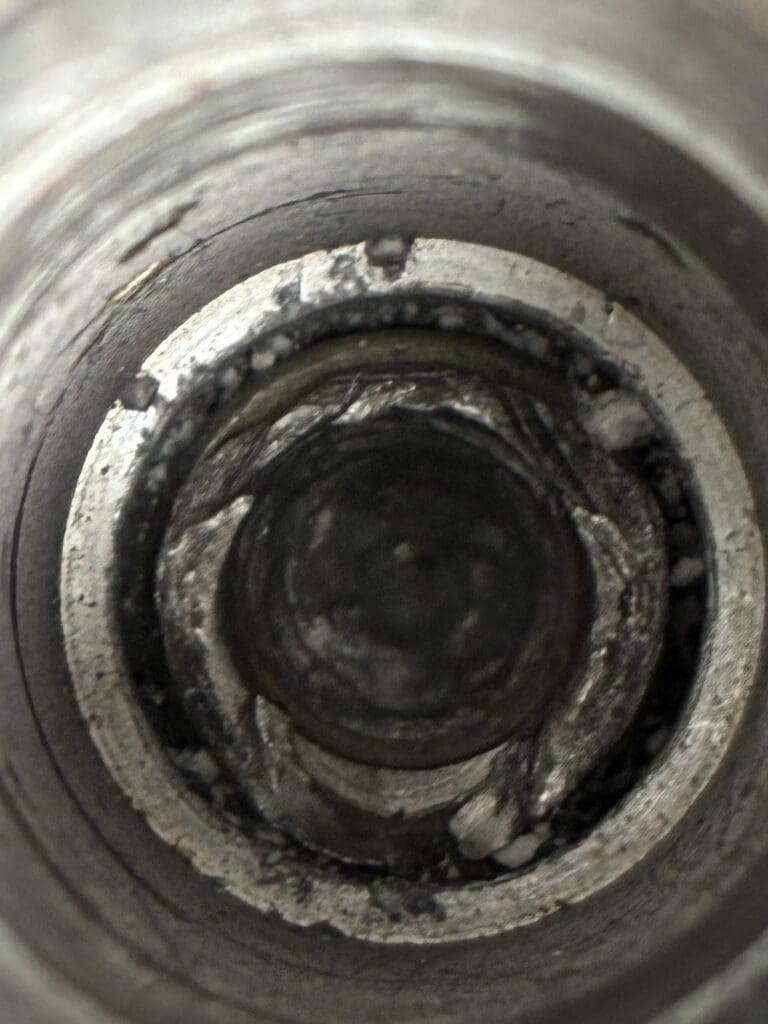 A close-up view of the interior of a metal pipe showing rust, mineral deposits, and concentric circular patterns.