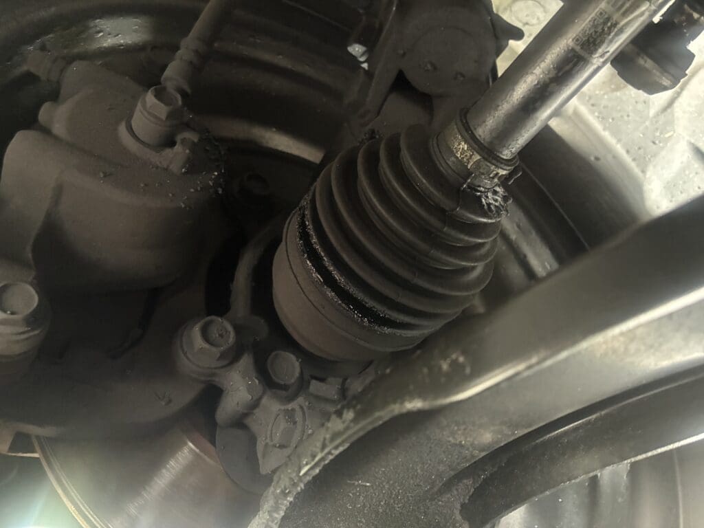Close-up view of a vehicle's suspension system showing shock absorbers, springs, and metal components in an automotive workshop setting.