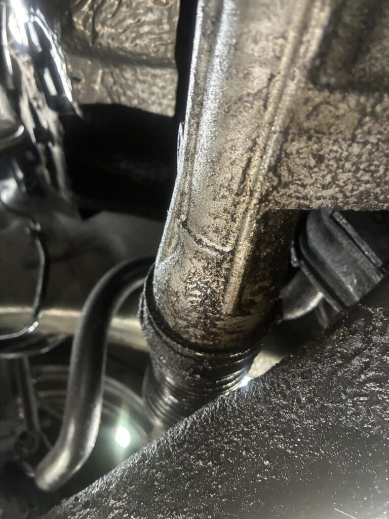 A detailed close-up of motorcycle components showing chrome details, leather straps, and mechanical parts in an indoor workshop setting.