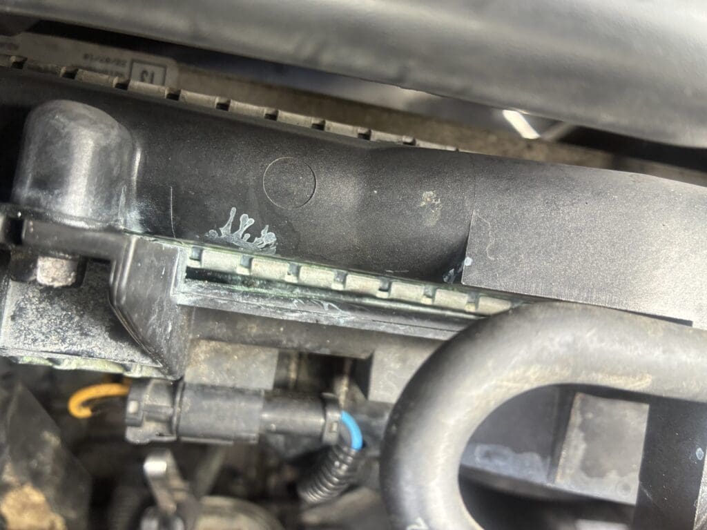 A close-up view of automotive engine components including fuel injectors, hoses, and connectors in a workshop or garage setting.