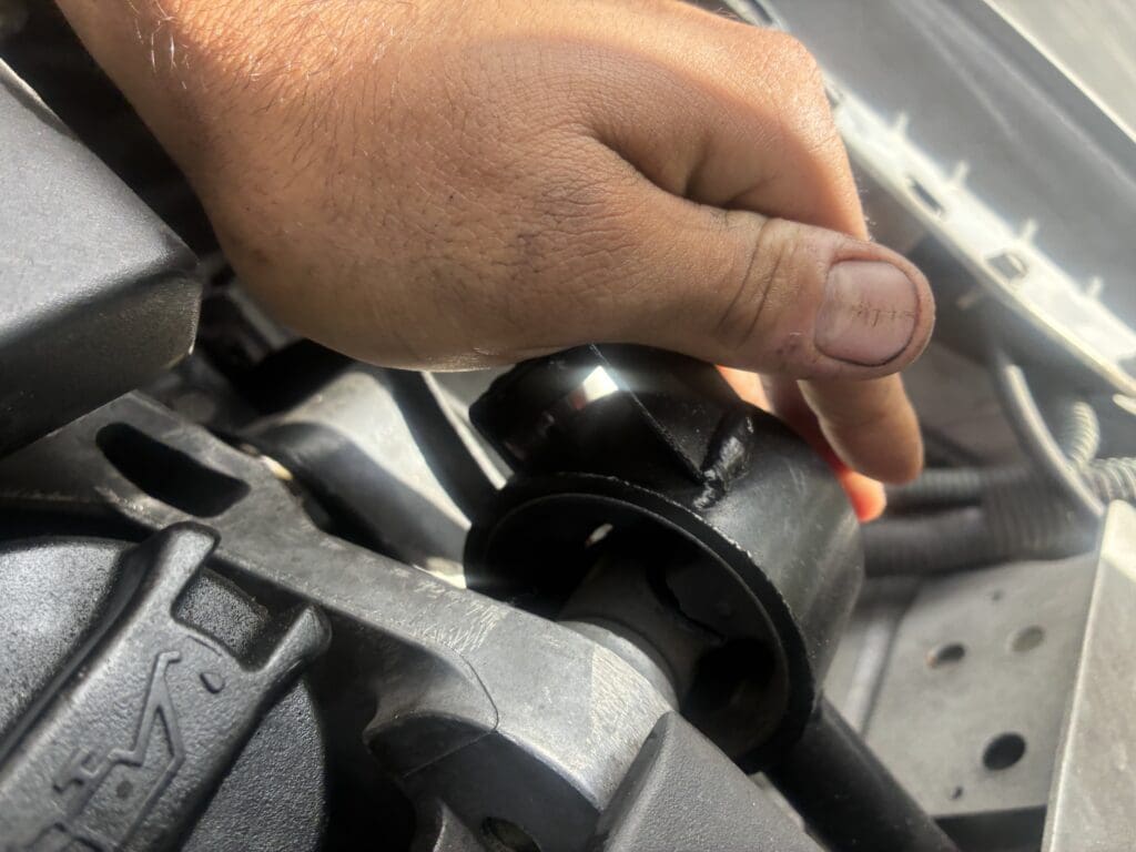 A close-up of a hand operating or adjusting a black mechanical lever or knob on industrial equipment.