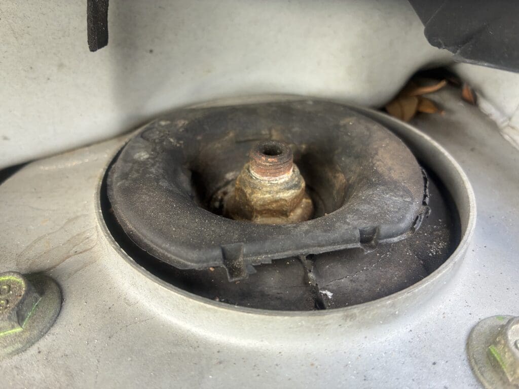 A close-up overhead view of a heavily corroded and deteriorated metal fixture mounted on a concrete surface, showing significant rust and decay.